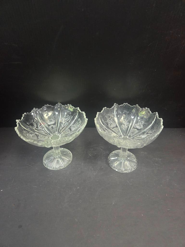 Pair of Pressed Glass Thistle Pattern Footed Compotes: Matching pair of footed compotes, fan-shaped bowl with scalloped/ruffled rim, thistle and floral pattern, on a round starburst-cut pedestal foot. Approx. 6"H x 7"W at rim each.