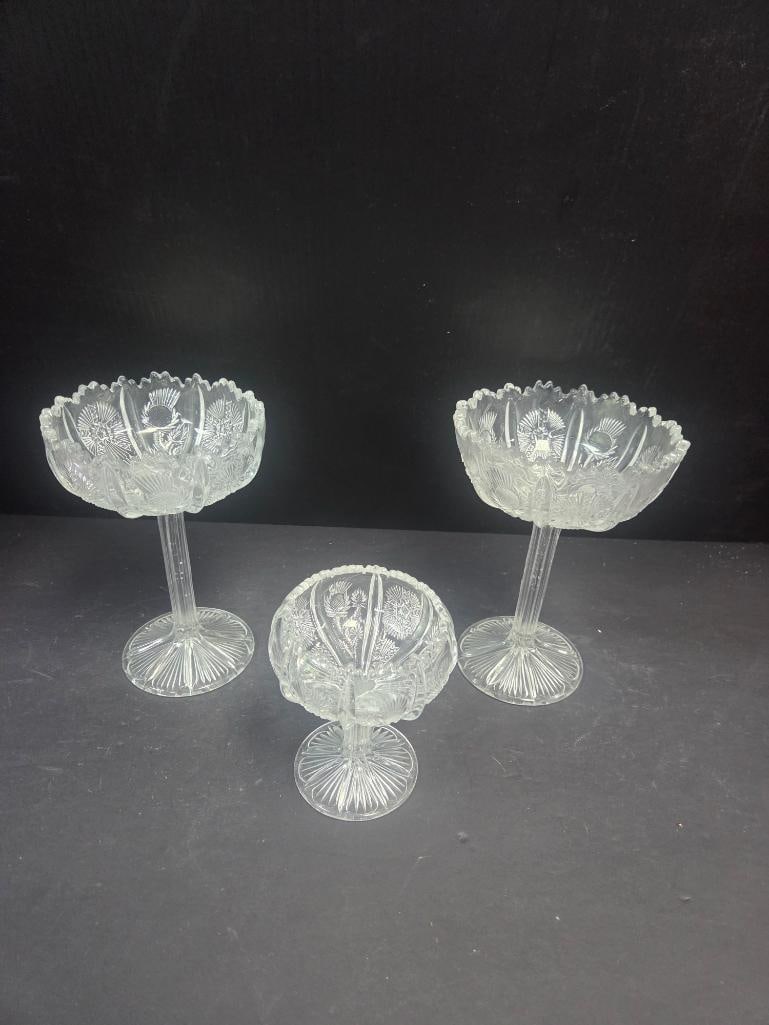 Grouping of Three Pressed Glass Tall-Stem Compotes: Tall stemmed compote, thistle pattern bowl, scalloped rim, on a slender pedestal stem. Approx. 6.5"H x 5"W.Tall stemmed compote, matching thistle pattern and stem (matches item above). Approx. 6.5"H x