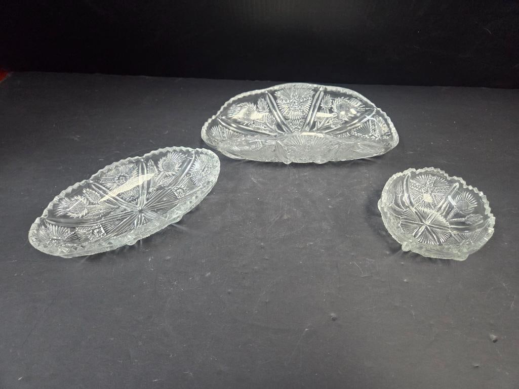 Pressed Glass Thistle Pattern Oval Trays and Round Dish: Small oval tray, thistle pattern, scalloped rim. Approx. 8"L x 4"W.Larger oval/boat-shaped tray, matching thistle pattern, scalloped rim (larger than item above). Approx. 10"L x 5"W.Small round