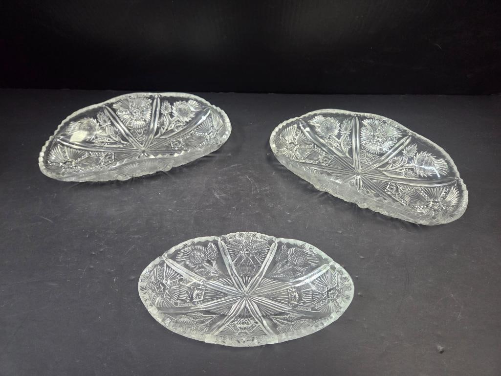 Pair of Pressed Glass Thistle Pattern Oval Trays and a Smaller Oval Tray: Oval boat-shaped tray, thistle pattern, scalloped rim. Approx. 10"L x 5"W.Oval boat-shaped tray, matching the item above. Approx. 10"L x 5"W.Smaller oval tray, matching thistle pattern, scalloped rim 