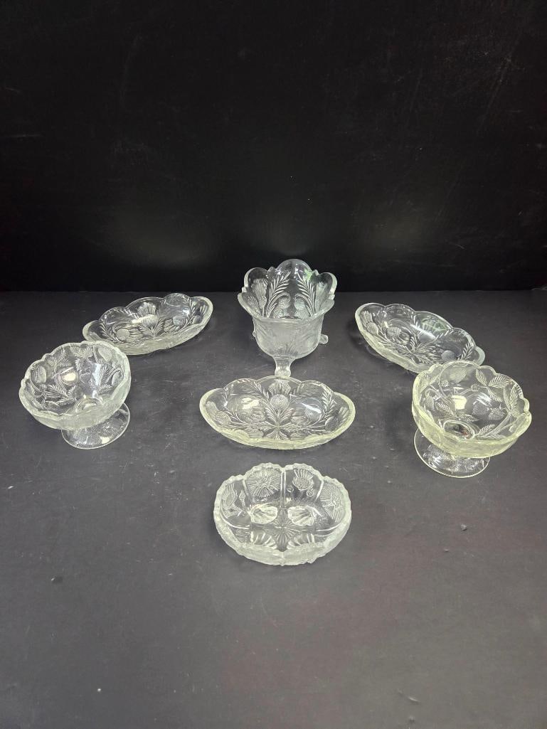 Mixed Grouping of Pressed Glass Fern Pattern Compotes and Dishes: Pair of small stemmed compotes, fern/leaf pattern, scalloped rim, footed. Approx. 4"H x 4"W each.Pair of oval shallow dishes, matching fern/leaf pattern, scalloped rim. Approx. 5.5"L x 4"W each.Small