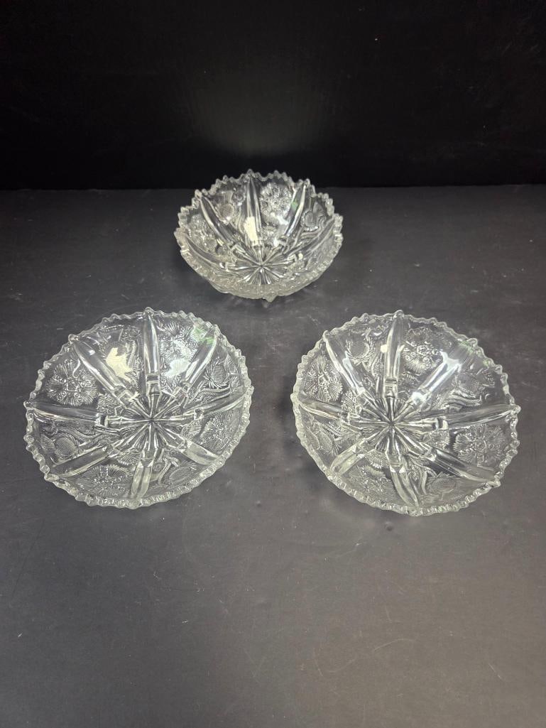 Pressed Glass Thistle Pattern Bowls: Pair of matching shallow round bowls, thistle pattern, scalloped rim, no feet. Approx. 2"H x 6"W each.Additional round bowl, thistle pattern, deeper profile with a more ruffled rim (does not match