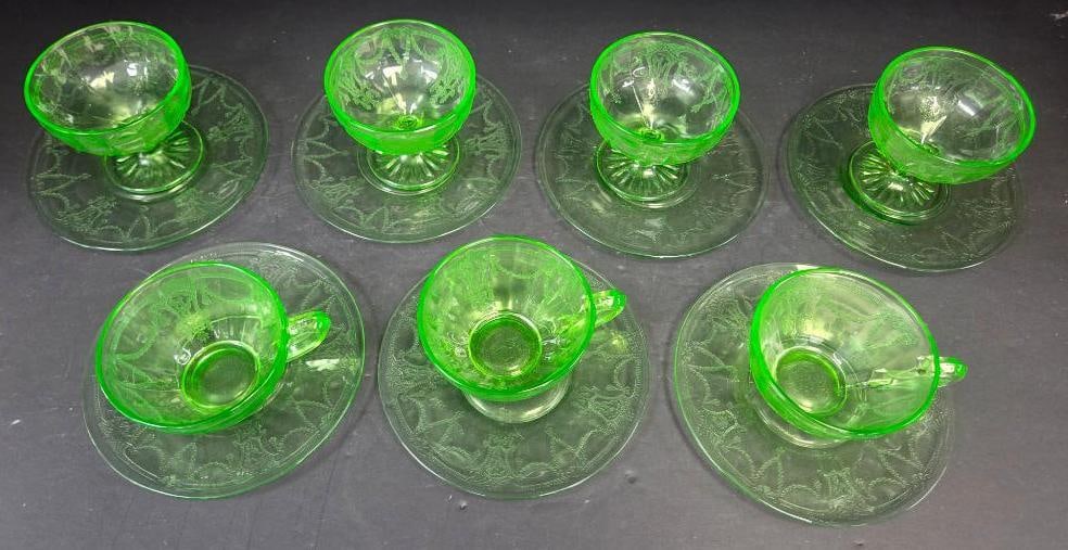 Grouping of Seven Green Depression Glass Cups and Saucers: 4 footed sherbet cups with matching saucers, green glass, etched pattern. Approx. 3"H x 4.5"W (saucer 6"W) each.3 flat cream-soup style cups with applied handle and matching saucers, green glass, etch
