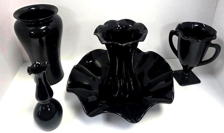 Grouping of Five Black Glass Vases and a Footed Mug: Tall cylindrical vase, black glass, flared rim. Approx. 9"H.Small bud vase, black glass, bulbous base. Approx. 6"H.Ruffled console bowl, black glass, wide scalloped rim. Approx. 3"H x 10"W.Fluted trum