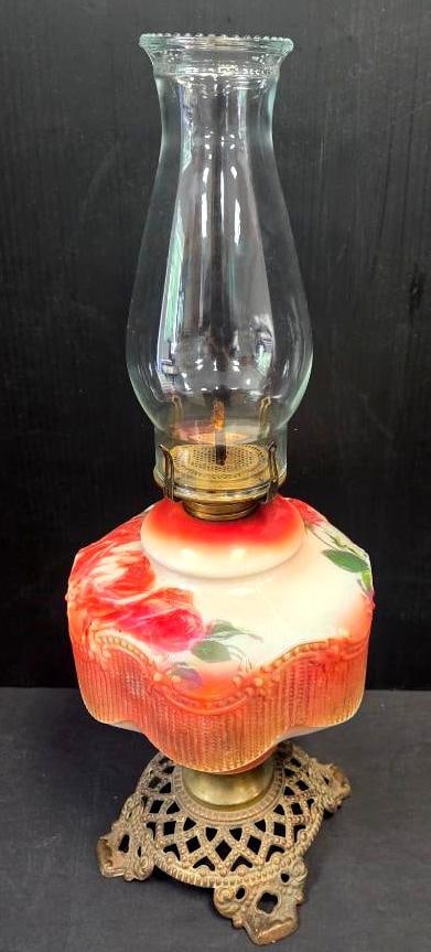 Antique Oil Lamp: Antique oil lamp with hand-painted milk glass font (red/pink roses and green leaves on a white/blush ground), brass burner with wick, clear glass chimney, and ornate cast metal filigree footed base,