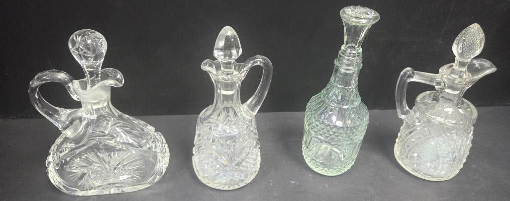 Pressed Glass Cruet Grouping, Four Pieces: Four pressed glass cruets/oil bottles with applied handles and matching faceted stoppers, each in a different diamond-point or fan-cut pattern; three are clear and one is pale green-tinted, approx.