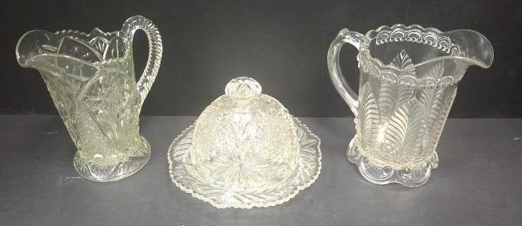 Pressed Glass Serving Pieces, Large Mixed Lot: Large mixed lot of pressed glass serving pieces, including two cut-pattern pitchers/creamers of differing pattern and size (one with a thistle and fan pattern on a scalloped foot, approx. 6" H; one