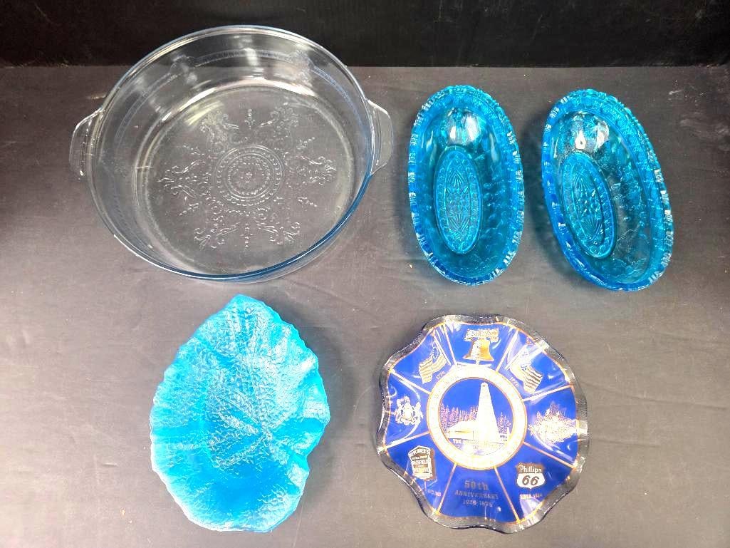Glass Baking Dish, Blue Pressed Glass, and Commemorative Advertising Plate, Mixed Lot: Clear glass round baking dish with two tab handles and an embossed floral medallion pattern, approx. 9" diameter, no maker's mark visible; two matching turquoise blue pressed glass oval dishes with