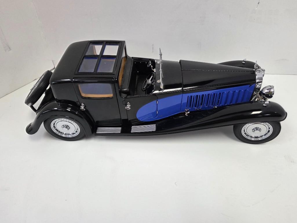 Black and Blue Bugatti Royale-Style Precision Model Car: Black precision diecast Bugatti Royale-style closed-cab touring car with blue accent panel along the lower body and grille, cream/tan interior trim, rear-mounted spare tire, glazed rear quarter