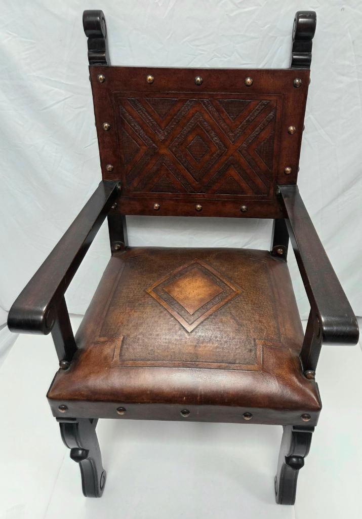 Spanish/Gothic Revival Armchair with Tooled Leather Back and Seat: Dark wood armchair in Spanish/Gothic Revival style, scrolled arm and back terminals, tooled brown leather back panel and seat with a geometric diamond/chevron pattern and brass upholstery studs,