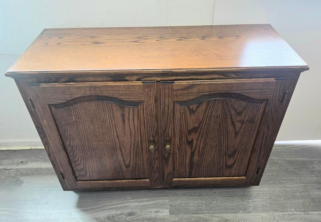 Oak Two-Door Cabinet with Arched Panel Doors: Oak two-door cabinet/sideboard, arched raised panel doors with brass drop pulls, interior fitted with two adjustable shelves creating divided storage compartments, approx. 48" W x 18" D x 32" H.