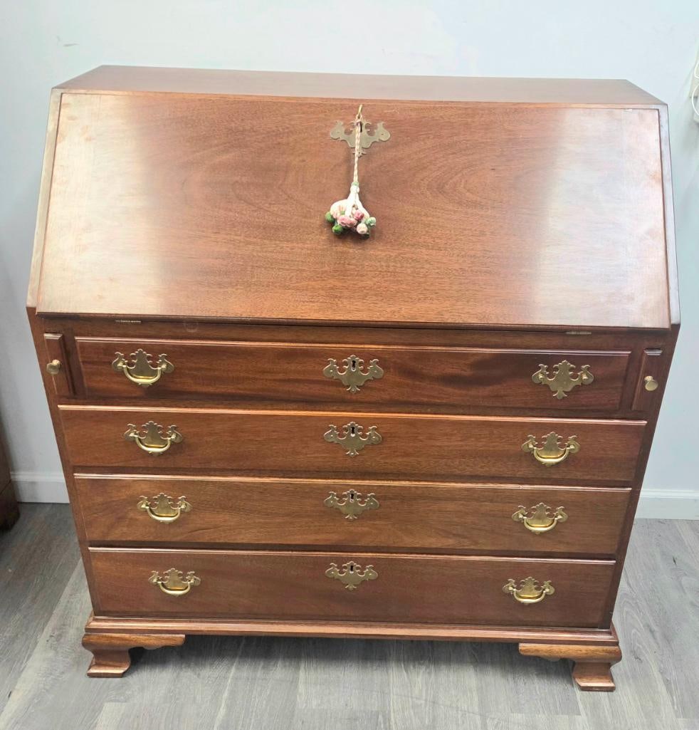 Mahogany Chippendale-Style Slant-Front Secretary Desk: Mahogany Chippendale-style slant-front secretary desk, four graduated drawers with brass bail pulls and pierced brass escutcheons (one hung with a decorative rope/tassel key fob), ogee bracket feet,
