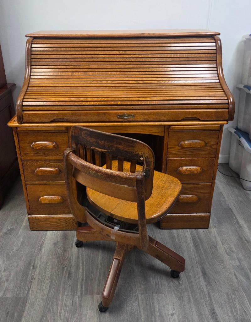 Oak Roll-Top Desk with Matching Oak Swivel Office Chair: Oak double-pedestal roll-top desk ("S" curved tambour), six drawers total, fitted interior with pigeonholes and small drawers behind the tambour, pull-out side slides, approx. 48" W x 30" D x 45" H.