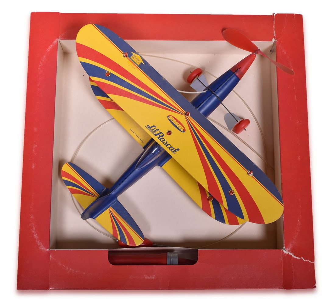 Stanzel Lil' Rascal Stunt Master Biplane Electromic Airplane In Original Box: A Stanzel Electromic Lil' Rascal biplane Stock No. 100, An Acrobatic Flying Sensation with Stunt-Master Control Handle in original packaging. The plastic packaging shows heavy discoloration from age a