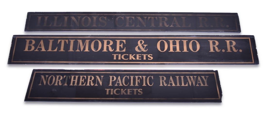 Group of Three Reproduction Railroad Ticket Depot Signs: A set of reproduction/fantasy glass ticket signs reverse painted on black with gold lettering, all on 3/16" glass. The Illinois Central sign measures 33 1/2" long x 3 1/2" wide and shows moderate fadi