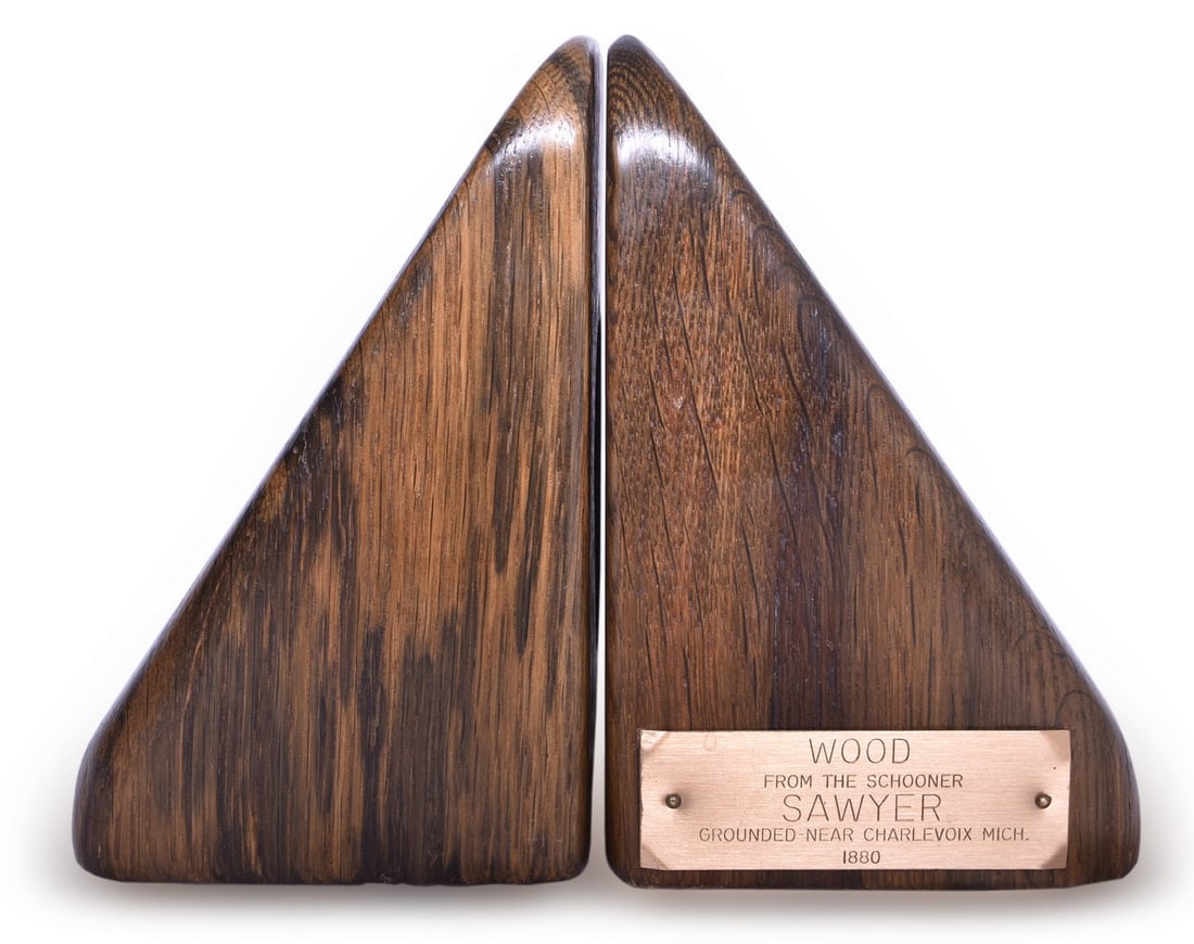 Great Lakes Shipwreck Co. Wood Bookends From The Schooner Sawyer Grounded 1880: A pair of bookends with a brass tag that reads Wood from the Schooner Sawyer Grounded Near Charlevoix Michigan 1880, made by Great Lakes Shipwreck Co., marked on the bottom with a sticker. Measure 6"