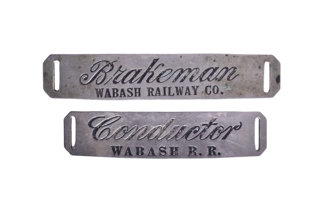 Wabash Railroad Conductor and Brakeman Nickel Cap Badges: Pair of Wabash Railway nickel cap badges both with black enameled lettering, no markers mark. Conductor badge measures 3 1/2" long and the Brakeman measures 4 1/8" long. Both hat badges show general u