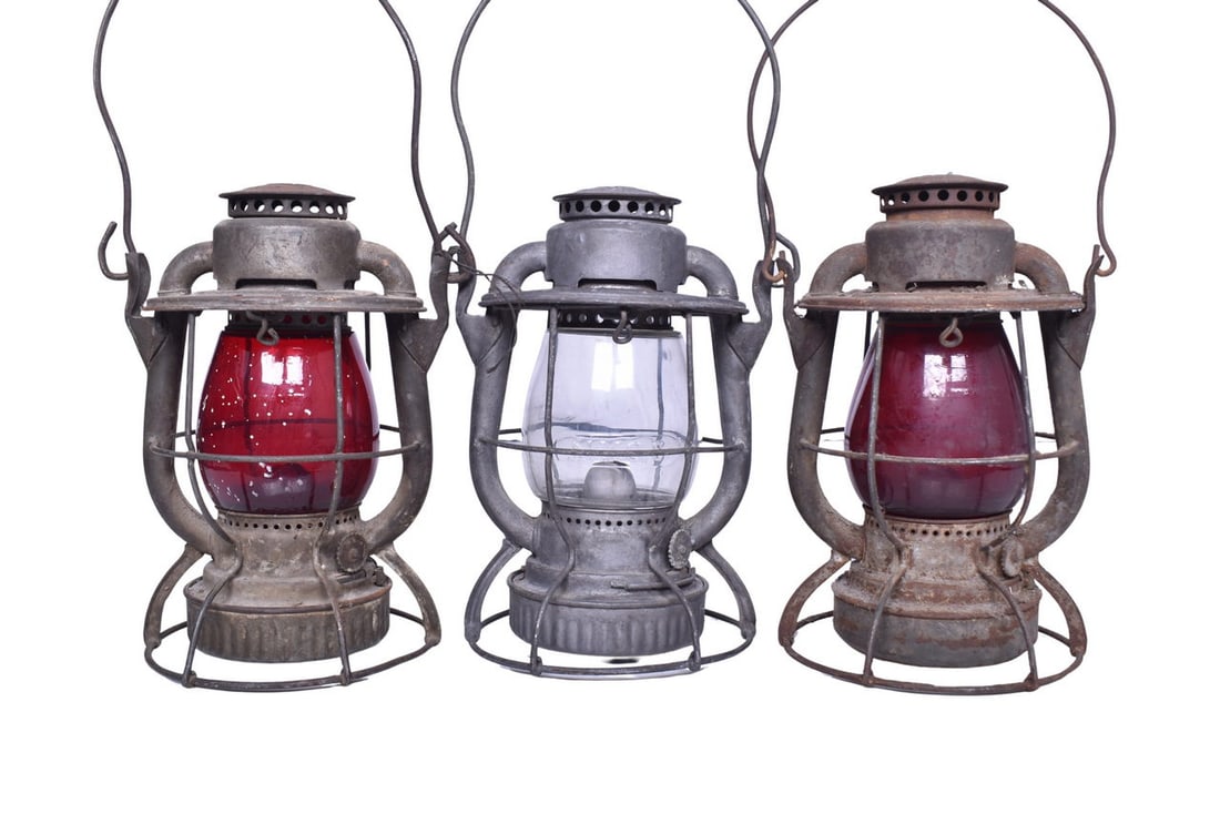 Trio of New York Central Railroad Dietz Lanterns: Three Dietz lanterns, each with either NYCS or NEW YORK CENTRAL embossed on the shoulder. Bodies are all in good condition with mild surface rust and staining. Burner pots and founts are all present.
