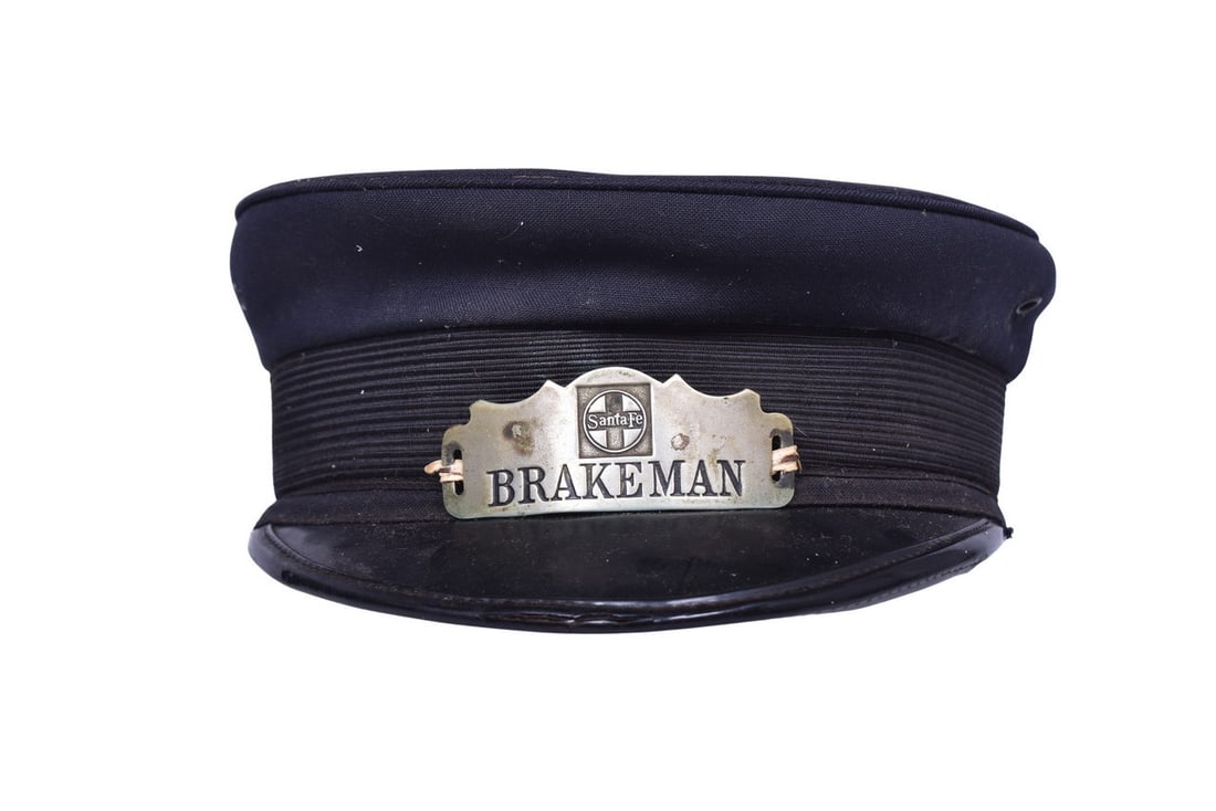 M.H. Grossman Railroad Uniform Cap with Nickel Santa Fe Brakeman: M.H. Grossman cap with missing size info, decorated with a nickel Santa Fe Brakeman badge attached with wire twist ties. Badge has mild enamel wear and small spots of staining / tarnish. Cap is in goo