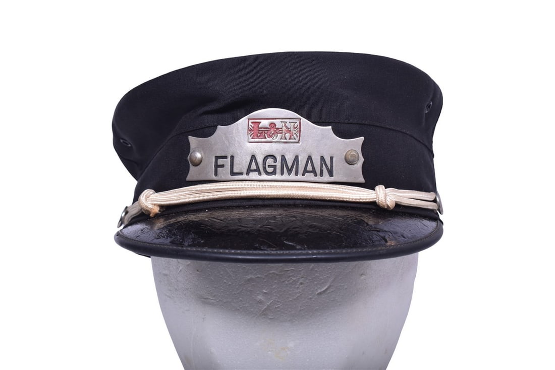 Louisville and Nashville Railroad Flagman Cap with Nickel Badge: A Pettibone railroad uniform cap with a nickel L&N Flagman badge attached by brads. Cap also has two silver L&N buttons and a white visor rope. Badge has some enamel wear in the red 'N' and the '&'.