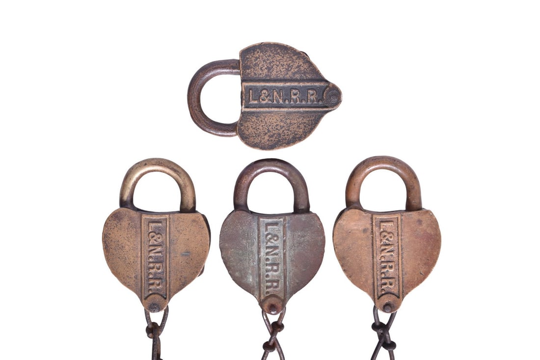 Four Louisville and Nashville Railroad Heart-Shaped Brass Locks: Four brass heart-shaped locks with each one cast with L&N RR in a panel across the front, and each with a key cover reading "To Get Key Out Close The Lock". Each lock also has a code stamped on the