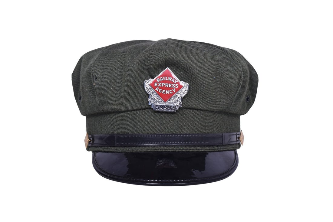 A size 7 1/4 cap made by the Natow Uniform Corp. decorated with a Railway Express Agency cap badge: A size 7 1/4 cap made by the Natow Uniform Corp. decorated with a Railway Express Agency cap badge and two brass REA side buttons. Cap is in good condition, with two small holes in the left side of th