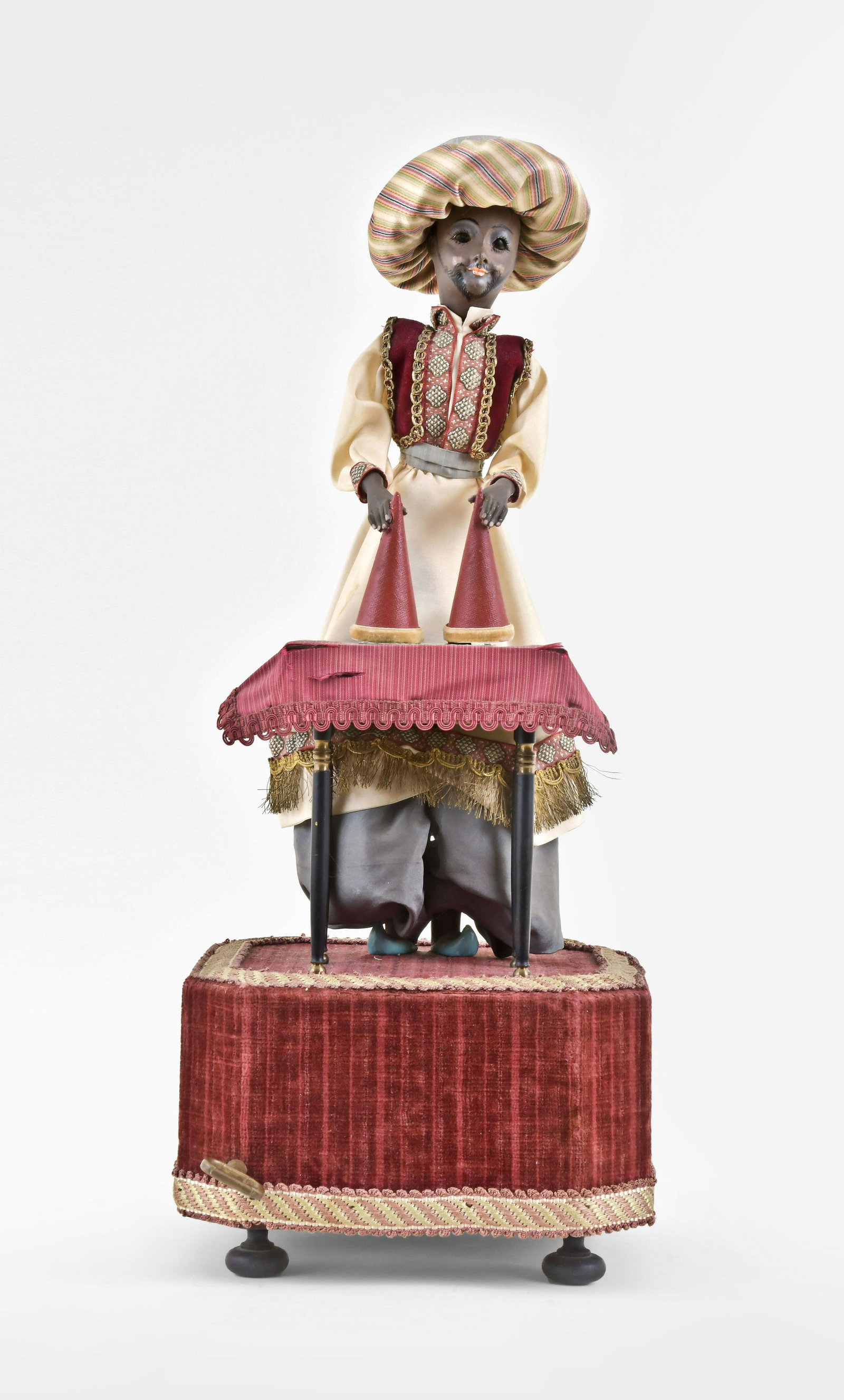 A 20th century Conjurer automaton by Jean Farkas: Jean Farkas, France, a 20th century Conjurer automaton, the turbanned figure in exotic costume, standing behind a red - draped table and holding two cones, turning his head while lifting and lowering 