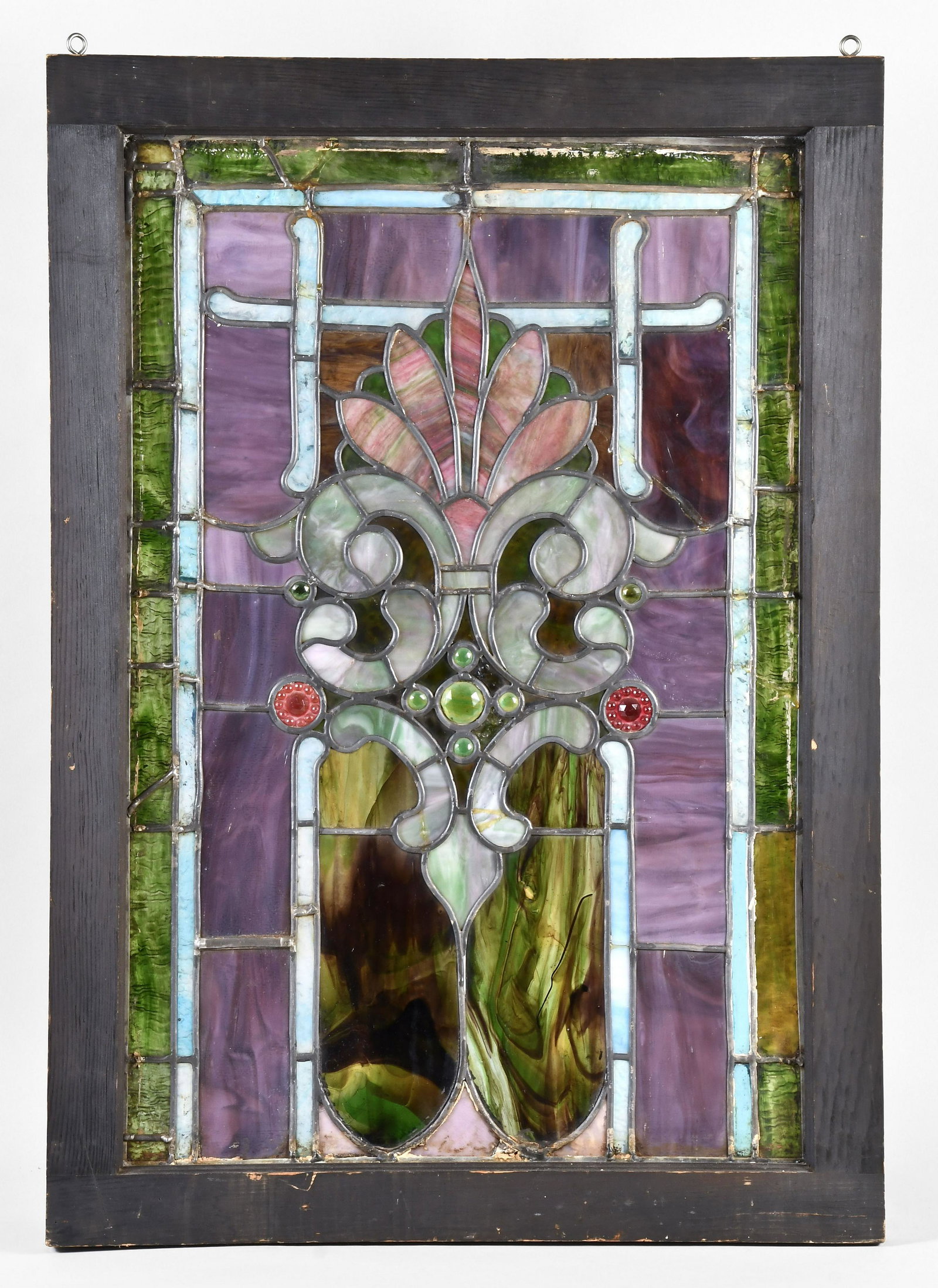 An attractive early 20th century stained glass window: An attractive early 20th century stained glass window, multi colored slag glass with with inverted lancet arches, crosses, and central palmette ornament with C scrolls, in a green painted wooden frame