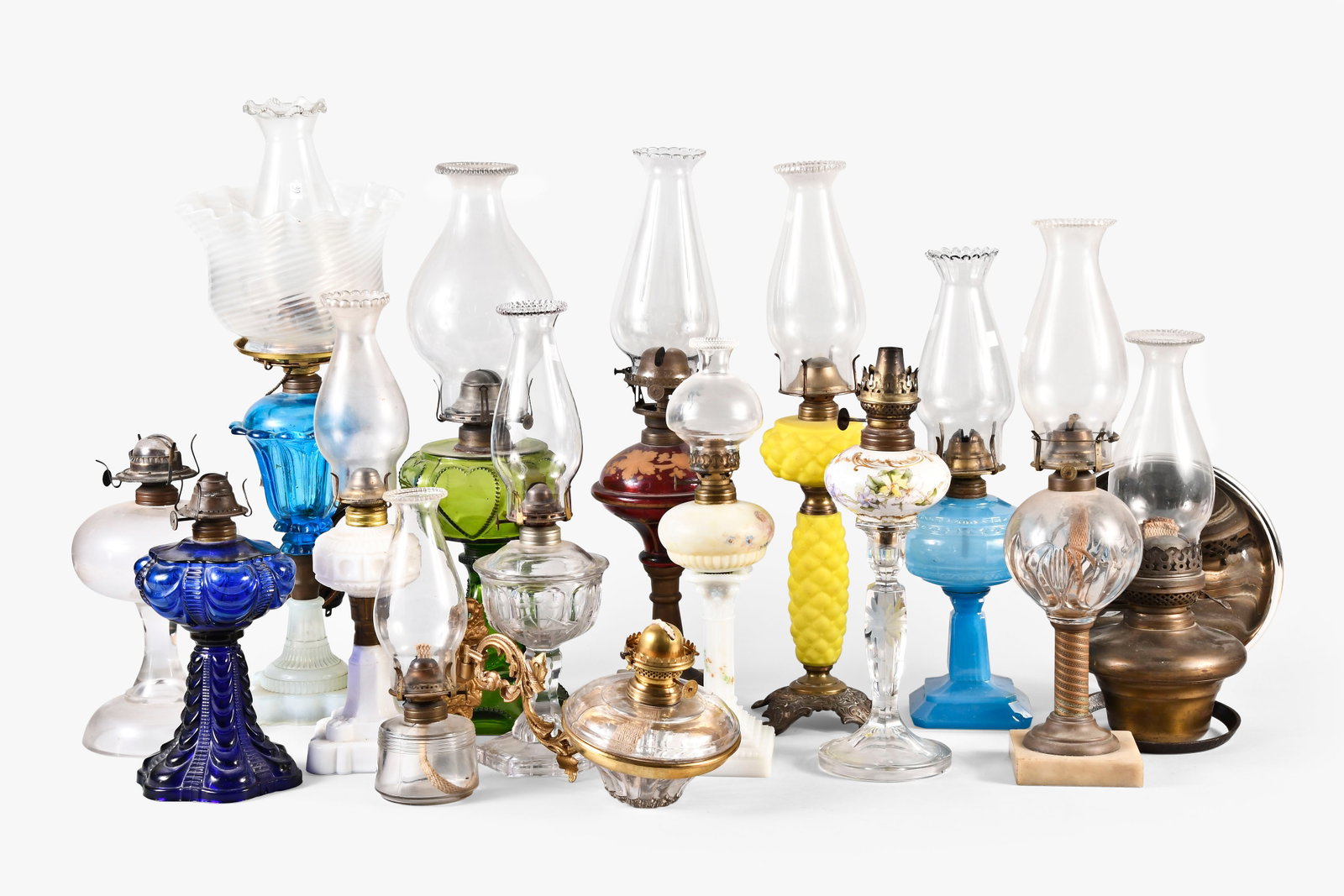 A lot of fifteen oil lamps: 15 (Fifteen) oil lamps including thirteen stand lamps including two peg lamps, one electrified whale oil, two milk glass, one yellow satin glass, one ruby, together with two bracket lamps, one with br