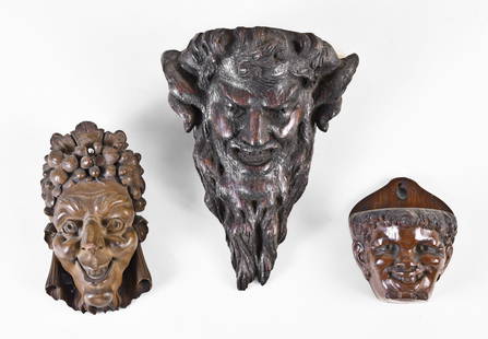 A lot of five late 19th and early 20th century face carved wooden items: 5 (Five) late 19th and early 20th century face carved wooden items including two wall pockets, both smiling and with slightly exaggerated features, an ornamental mask with exaggerated features and gra