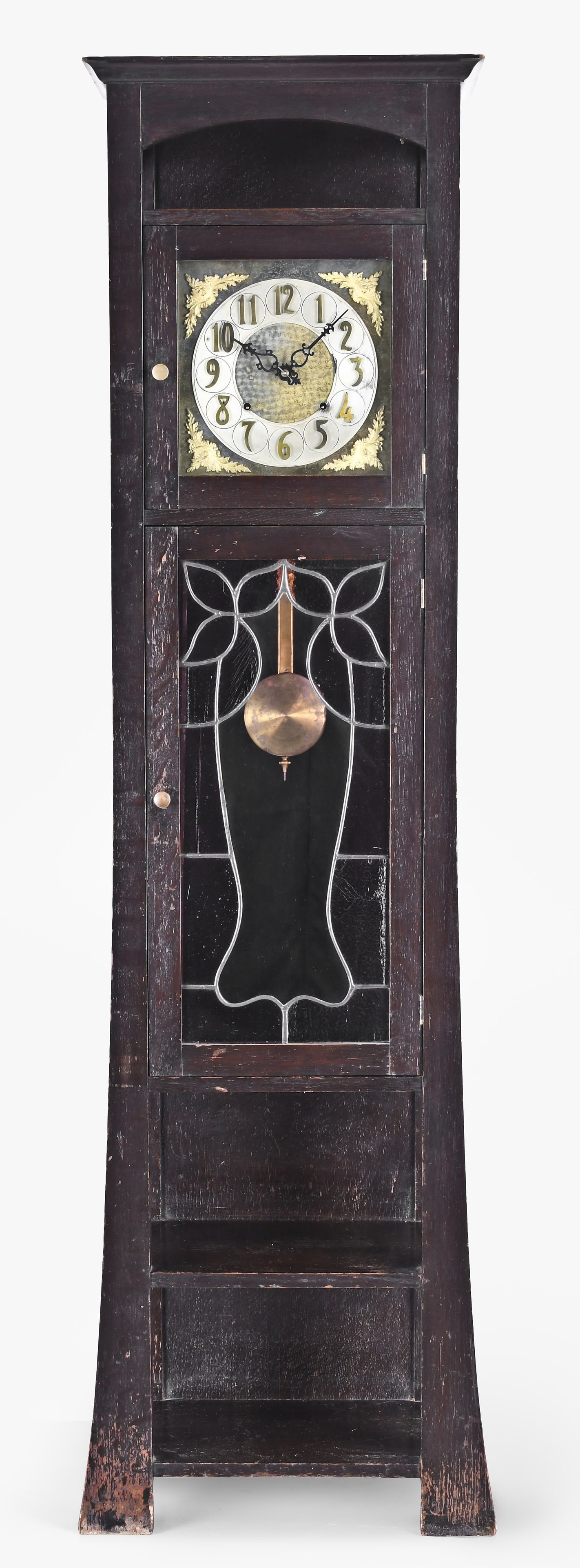 An Arts and Crafts style tall clock: An American tall clock in the Arts & Crafts style in a darkly stained solid oak case, flat top with arched cutouts below, lead glass panel inset into trunk door with light purple dimpled glasses over