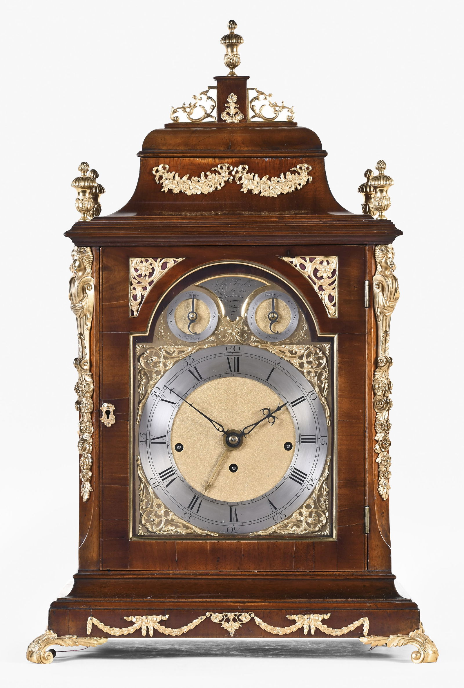 A large late 18th century English musical table clock signed John Taylor: John Taylor, London, a large late 18th century musical table clock, mahogany veneered bell top case with molded base, foliate ornamented scroll feet and gilt swag mounts, the door with fabric backed c