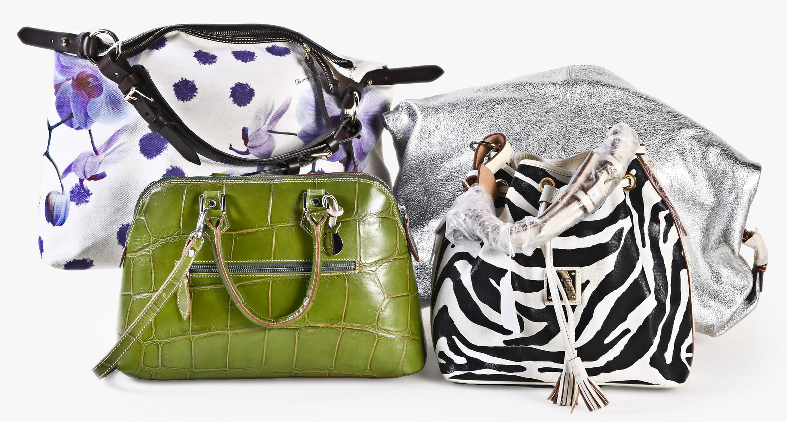 A lot of four late 20th - early 21st century Dooney & Bourke bags: 4 (Four) late 20th - early 21st century bags including a zip top satchel in green faux alligator leather and sales tag, a large shoulder bag with Orchid pattern print, a extra large silver Sac bag wit
