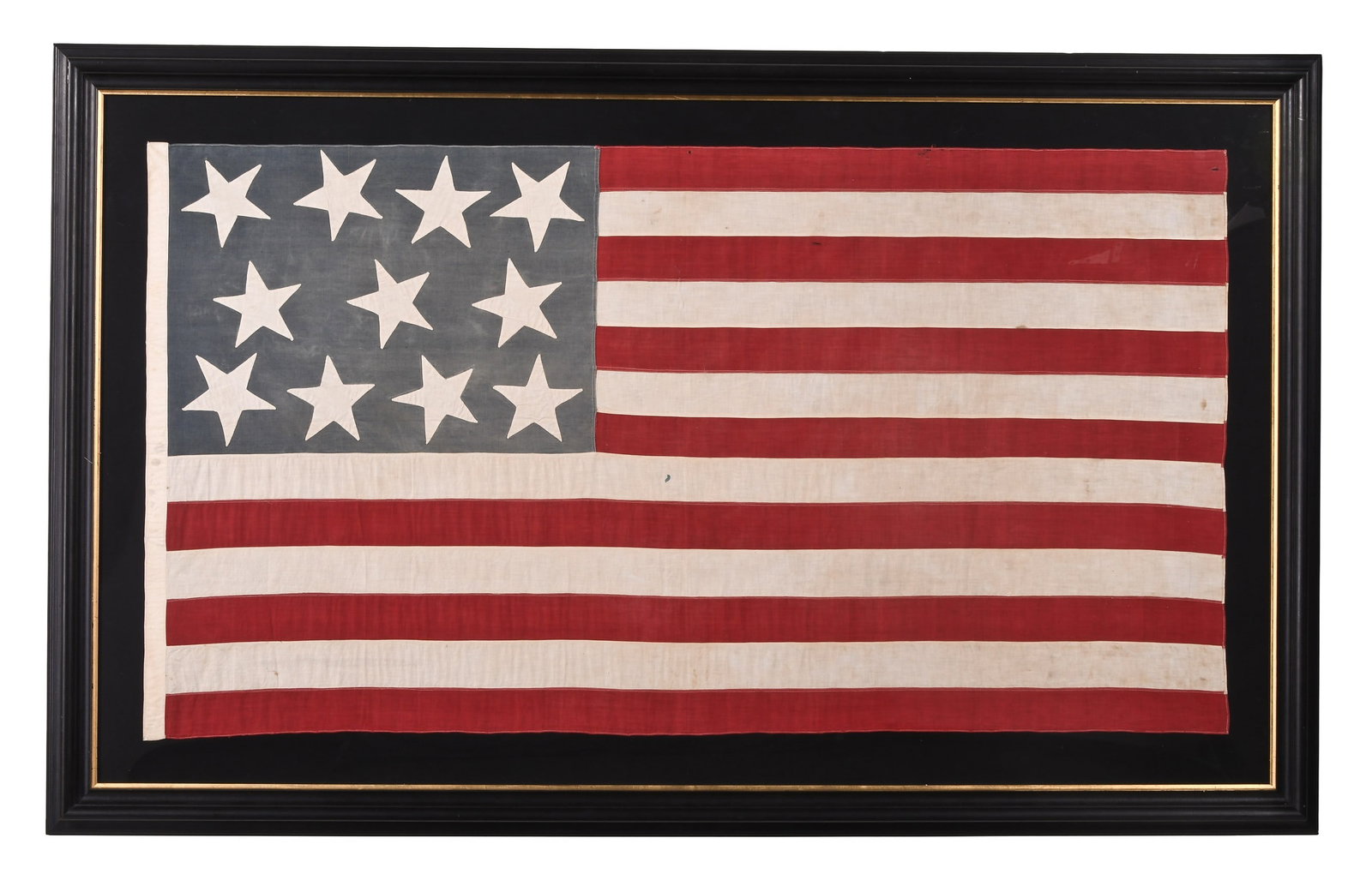 A large and unusual late 19th century 11 star American flag: A large and unusual late 19th century American cotton flag with 13 red and white stripes, and blue field with 11 stars, stitched to a black ground and contained in an ebonized frame with gilt liner, t
