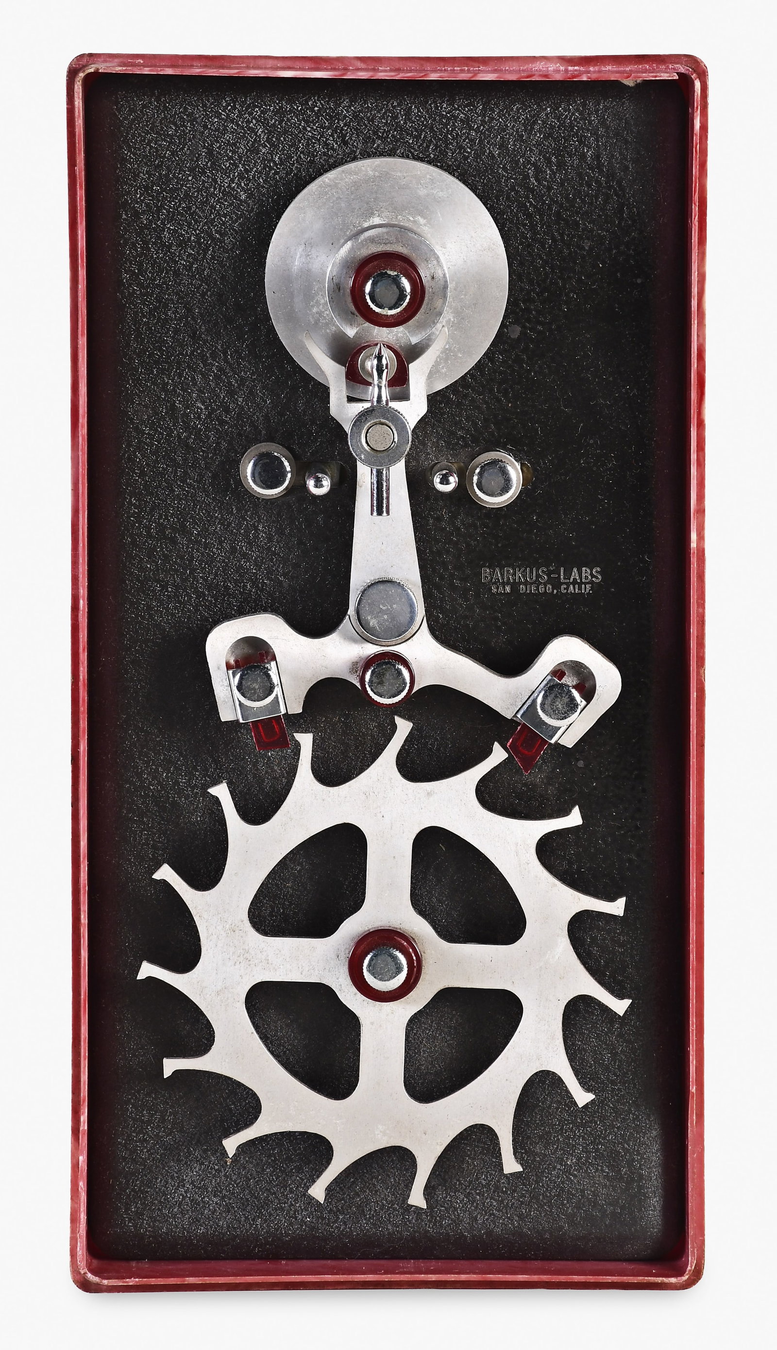 A mid 20th century Barkus Horological Laboratories lever escapement model with box: Barkus Horological Laboratories, San Diego, a mid 20th century lever escapement model, the metal components of aluminum and the jewels red plastic, mounted on a black painted metal base, the parts adj