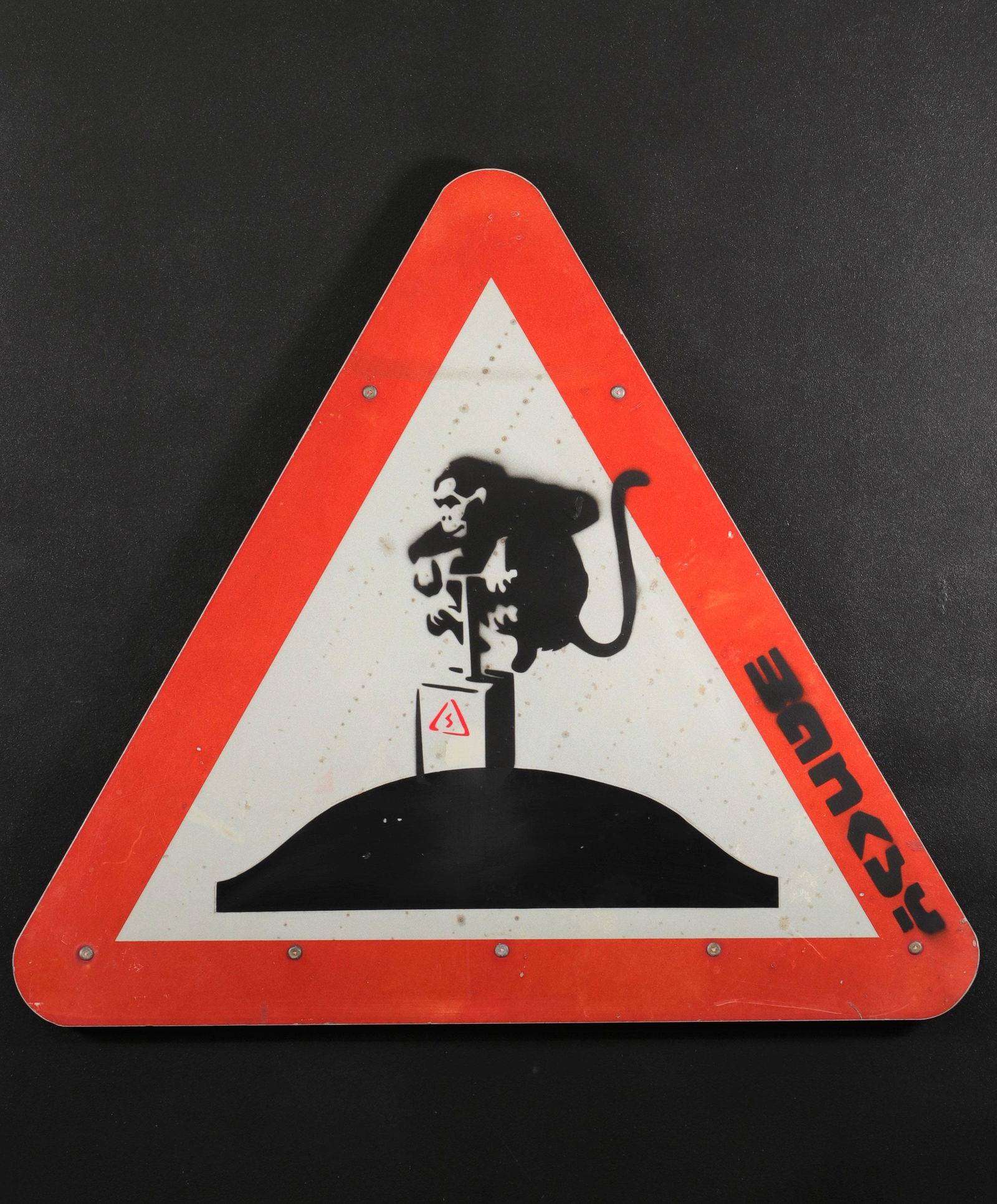 Banksy. Explosive Monkey.: "Banksy. Explosive Monkey. Black and red spray on road sign, representing a monkey which detonates a donkey. Signed" Banksy "in black spray. Dimensions: 60 x 68 cm. Provenance: - Private collection, L