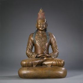 A Tibetan bronze statue of a monk, painted in gold, from the 15th century or later.