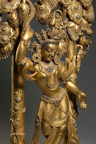 A Tibetan gilt bronze standing Avalokiteshvara statue inlaid with turquoise, dating from the 15th to