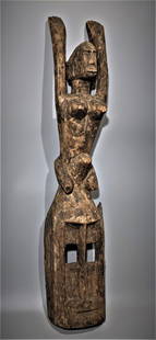 An Antique Dogon Figural Mask: At top, a female figure with legs wrapped around the horn of the mask. Possibly 19th century or earlier. 26.75" Height. Raised arms in the archaic Tellem manner. From Mali , an example well worn from