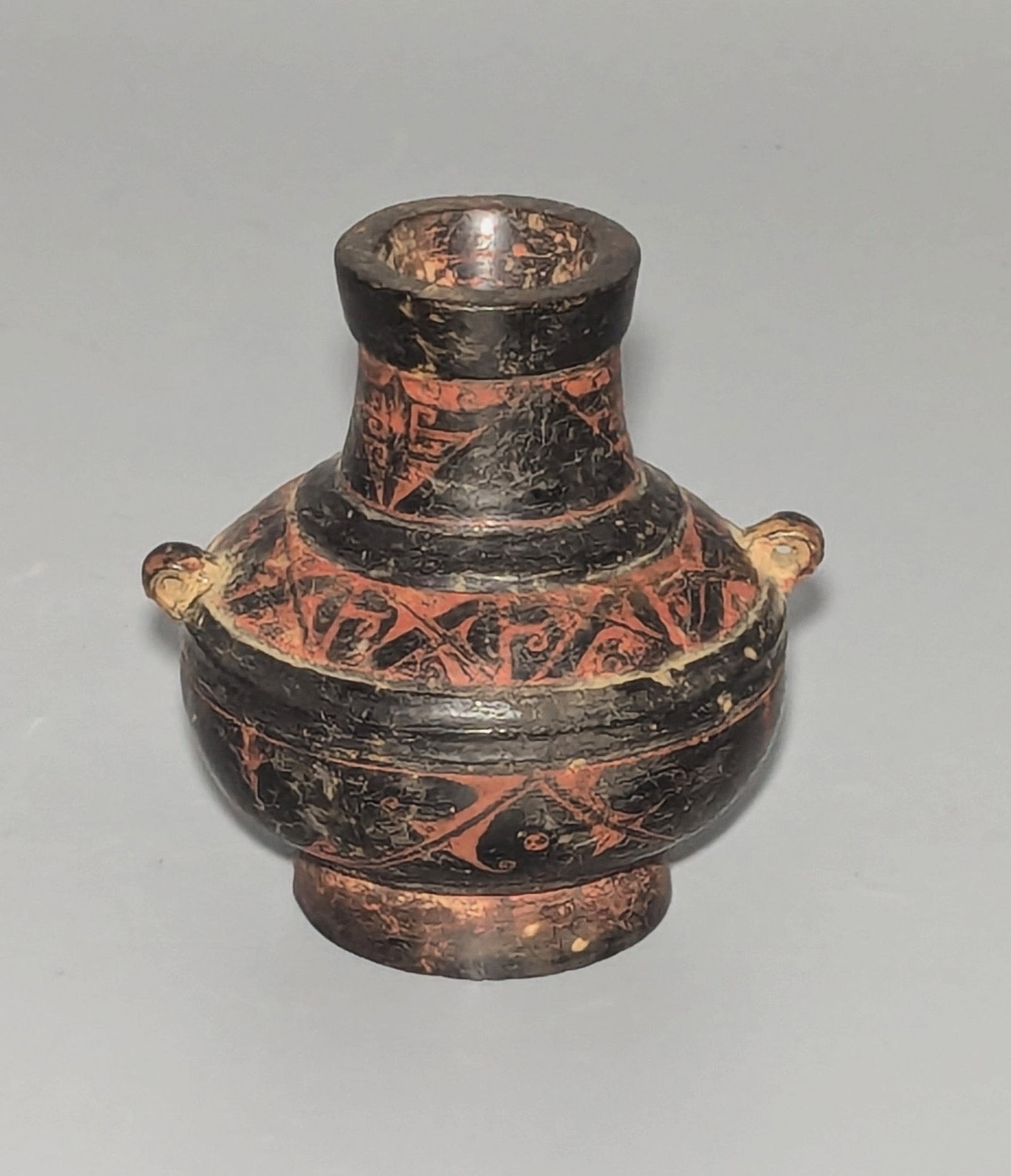 Possibly Ancient South Italian Miniature Pottery Vessel, Hellenistic Period or Later: A pottery vessel in the Apulian style, probably Southern Italy. The small vessel of compressed globular form, raised on a circular foot and surmounted by a cylindrical neck flanked by a pair of pierce