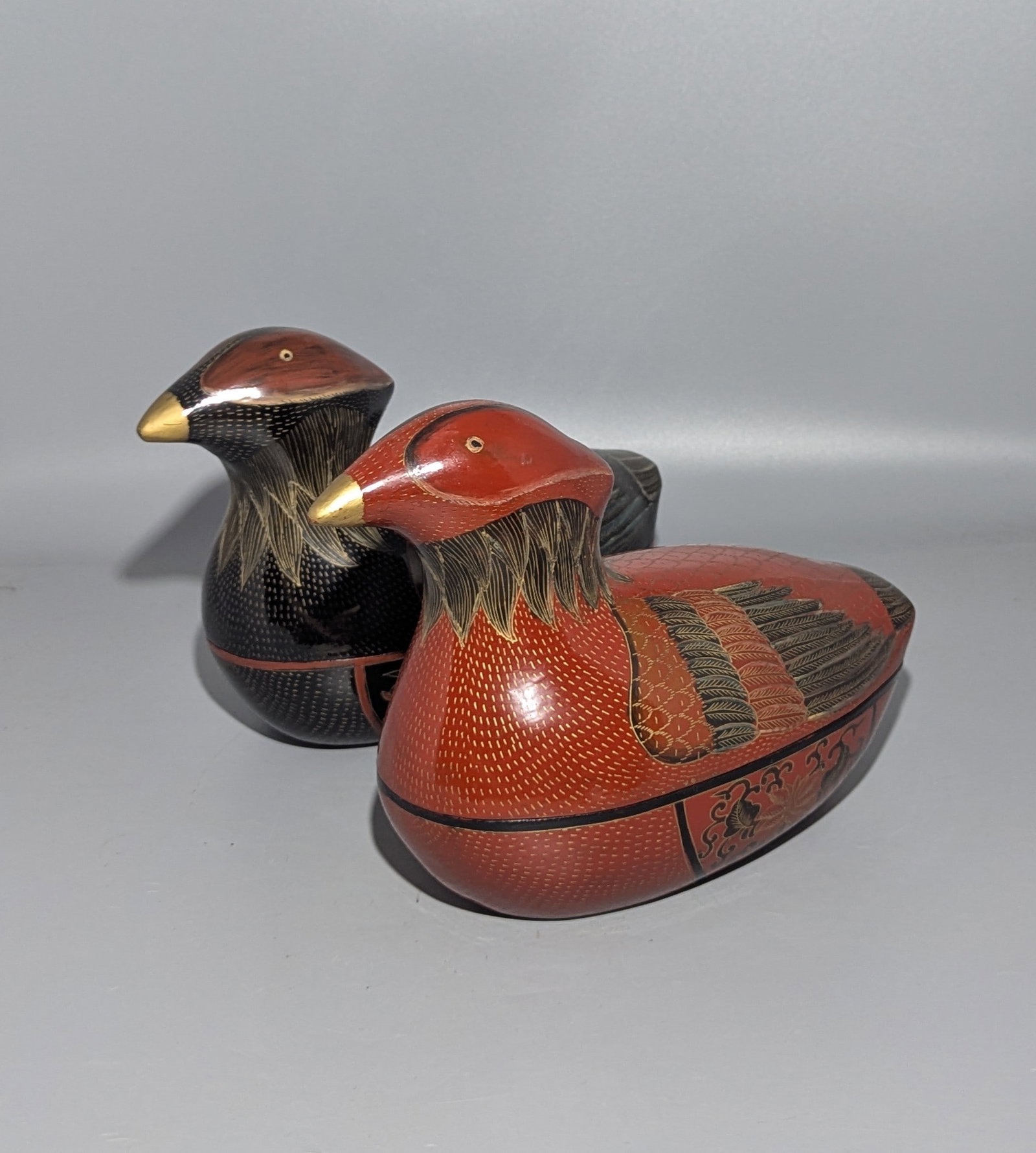 Pair of Burmese Lacquered Hintha Bird-Form Boxes, Myanmar: A pair of decorative Burmese lacquered boxes modeled in the form of stylized hintha or hamsa birds, one predominantly red and the other black, each finely decorated with incised feather patterns and m