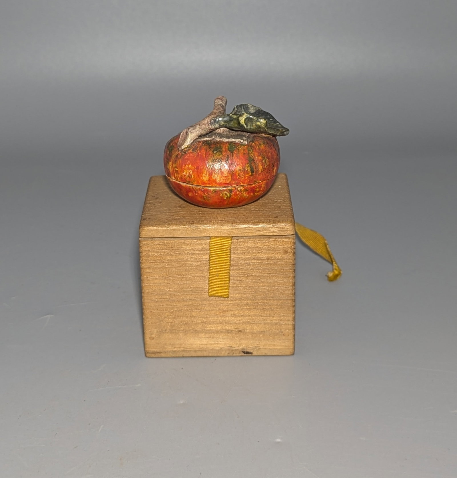 Japanese Glazed Ceramic Persimmon-Form Kogo with Wooden Box: A Japanese glazed ceramic k?g? or incense container modeled in the form of a ripe persimmon, finished in mottled orange-red and green glazes and surmounted by a naturalistically modeled stem and leaf.