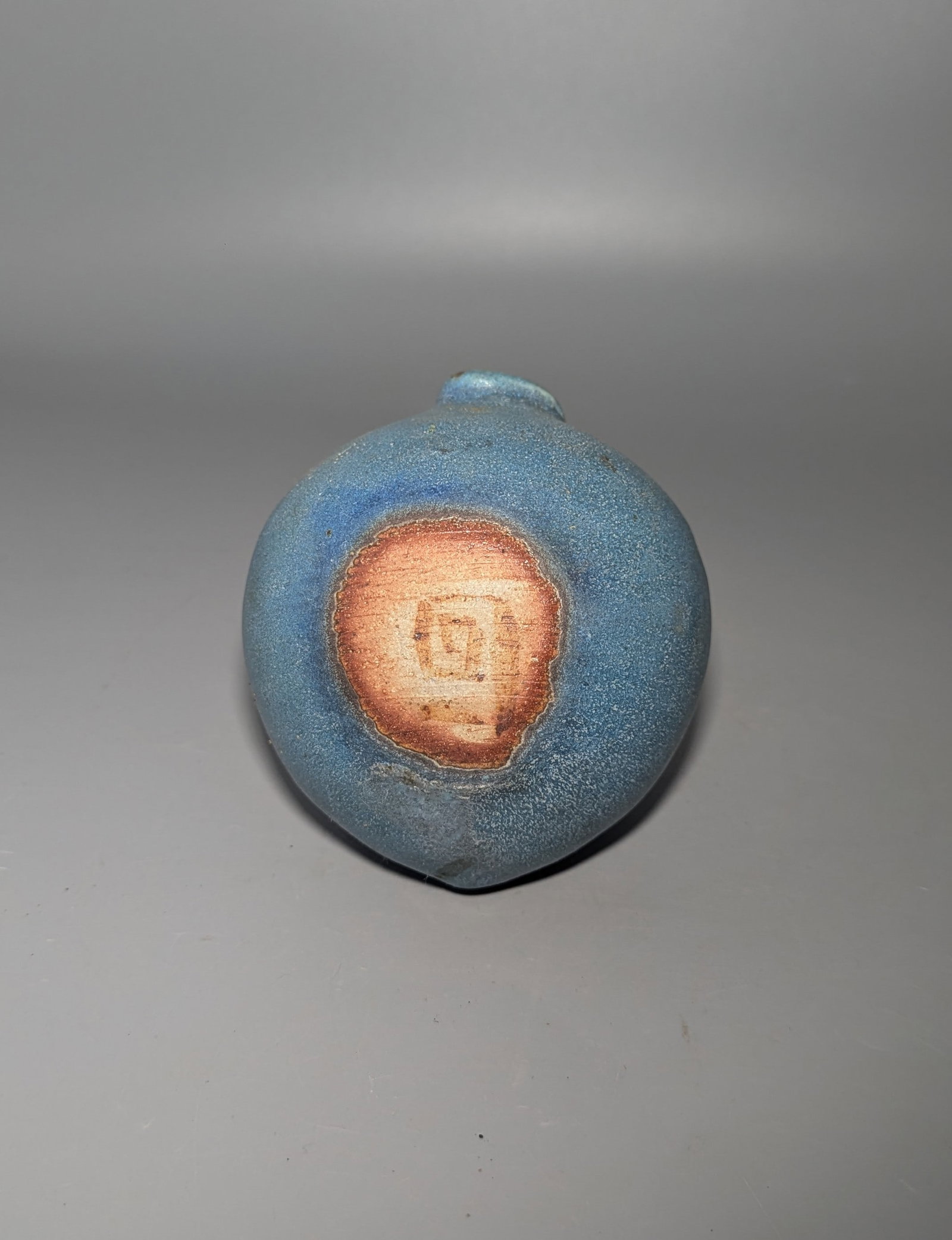 Western Studio Pottery Jun-Style Blue Glazed Vase: A hand-thrown studio pottery vase of rounded asymmetrical form with a pinched, off-center mouth, covered in a finely textured sky-blue Jun-style glaze with a localized lavender-purple splash below the