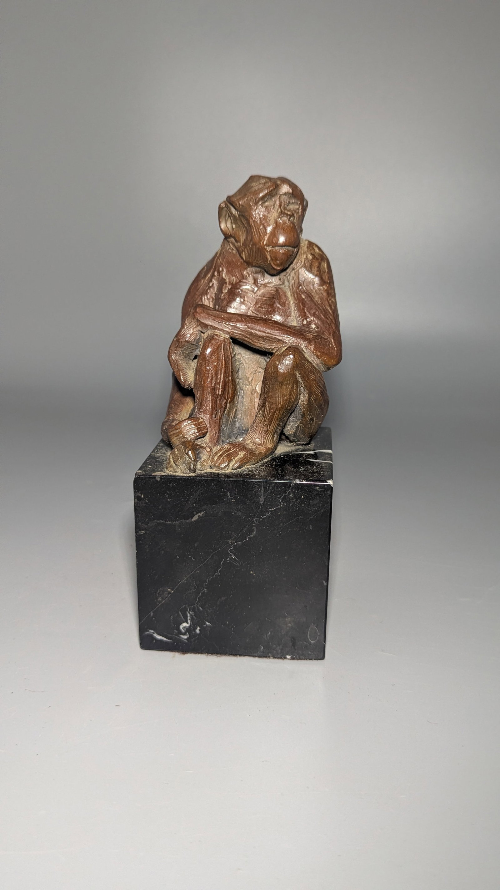 Bronze Seated Chimpanzee Sculpture: Patinated bronze sculpture depicting a seated chimpanzee, mounted on a polished black marble base. Incised with artist signature, dated 1993, and numbered 2/25 from a limited edition. Size: Approx. 9 