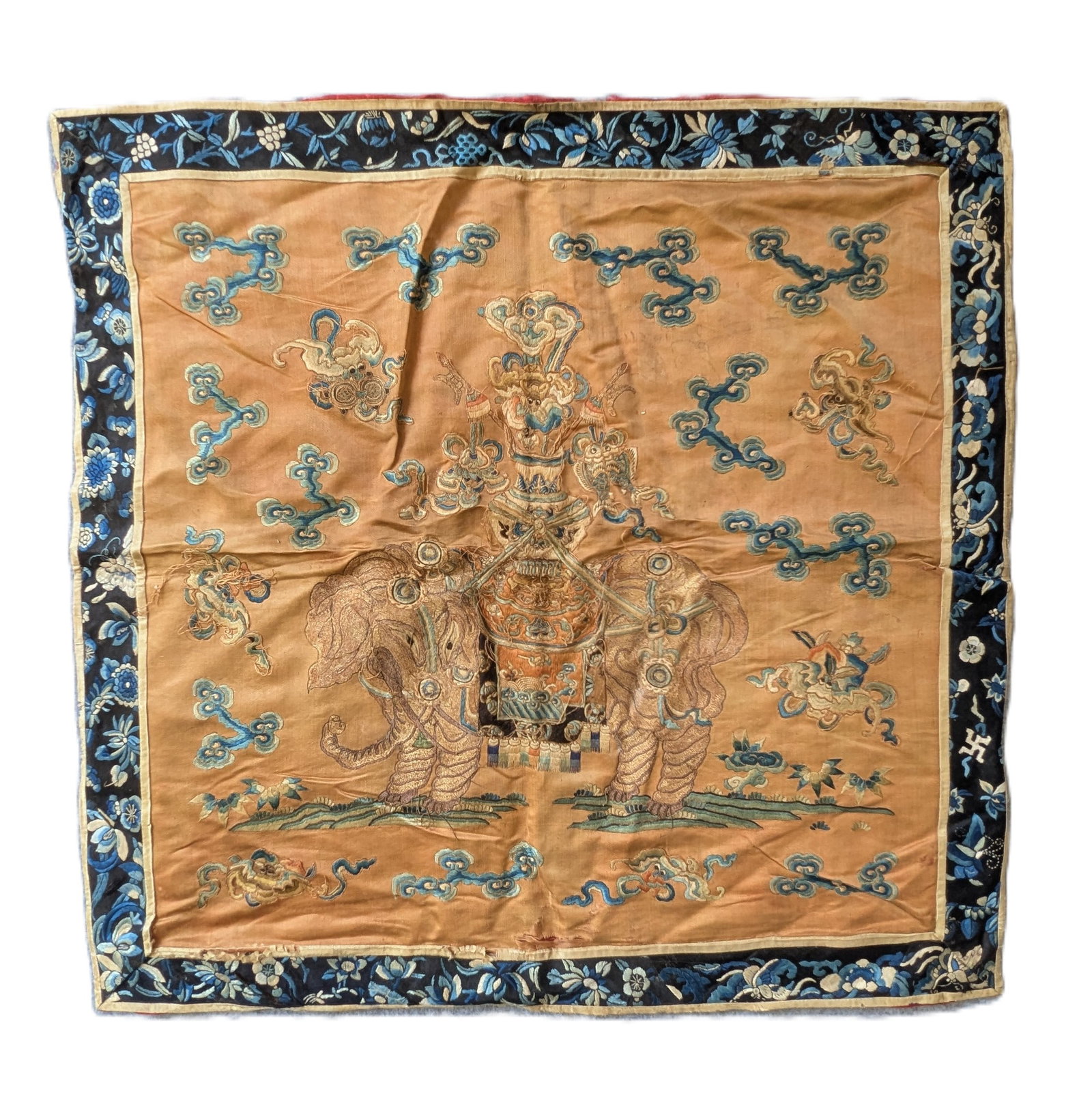 Chinese Late Qing Embroidered Silk Elephant Panel: A late Qing Dynasty Chinese embroidered silk panel, likely originally made as a decorative cushion or chair-back cover. The apricot-gold silk ground is centered by a richly caparisoned elephant suppor