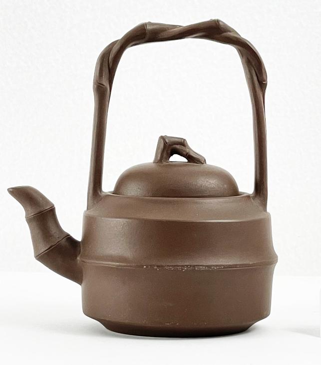 Chinese Yixing Clay Teapot: Chinese Yixing clay teapot with an arching, vine motif handles. Faintly impressed mark on the underside as seen. Dimensions: 5”W x 5.5”T x 3.75”D