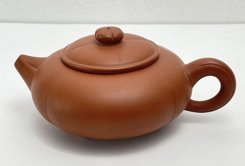 Chinese Yixing Clay Teapot: Chinese Yixing clay teapot with a flattened square shape and circular ring handle. Impressed marks on the undersides of pot & lid as seen. Dimensions: 5.5”W x 2.75”T x 4.25”D