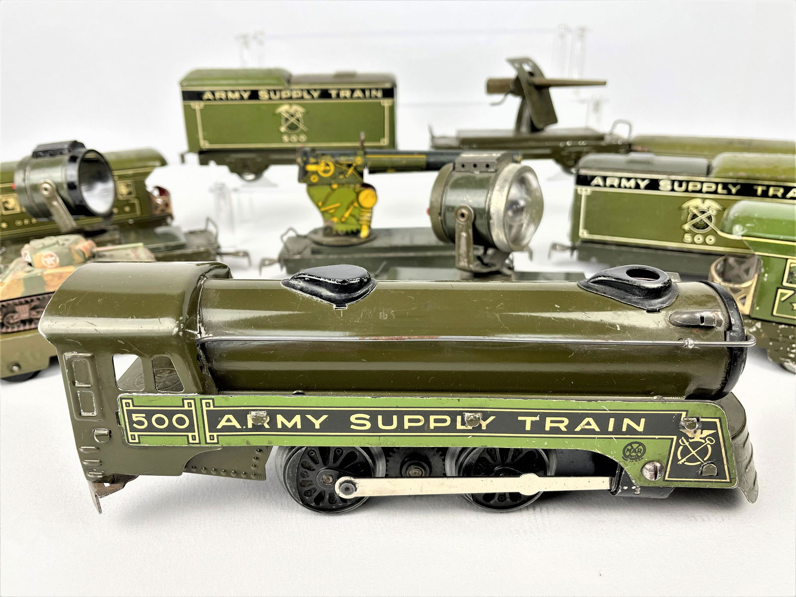 Marx Prewar Army Supply Train No. 500 Set: Prewar Marx tin litho Army supply train with No. 500 steam locomotive, (5) box cars, and (5) flat cars with equipment as seen including spot lights, machine guns and more. Untested. Vintage wear/rubbi