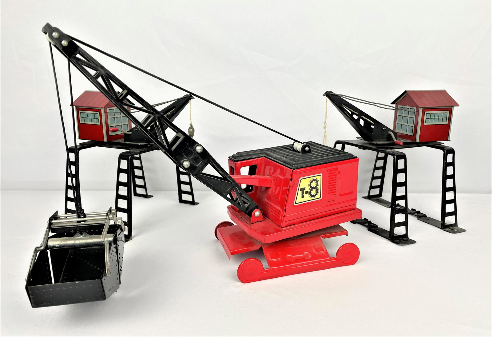 Three Tin Overhead Bucket Cranes: Three vintage tin/metal cranes including two (2) Marx 422 overhead elevated gantry derrick tin litho O scale cranes and an unmarked vintage larger metal bucket crane. Vintage wear as seen. See photos 