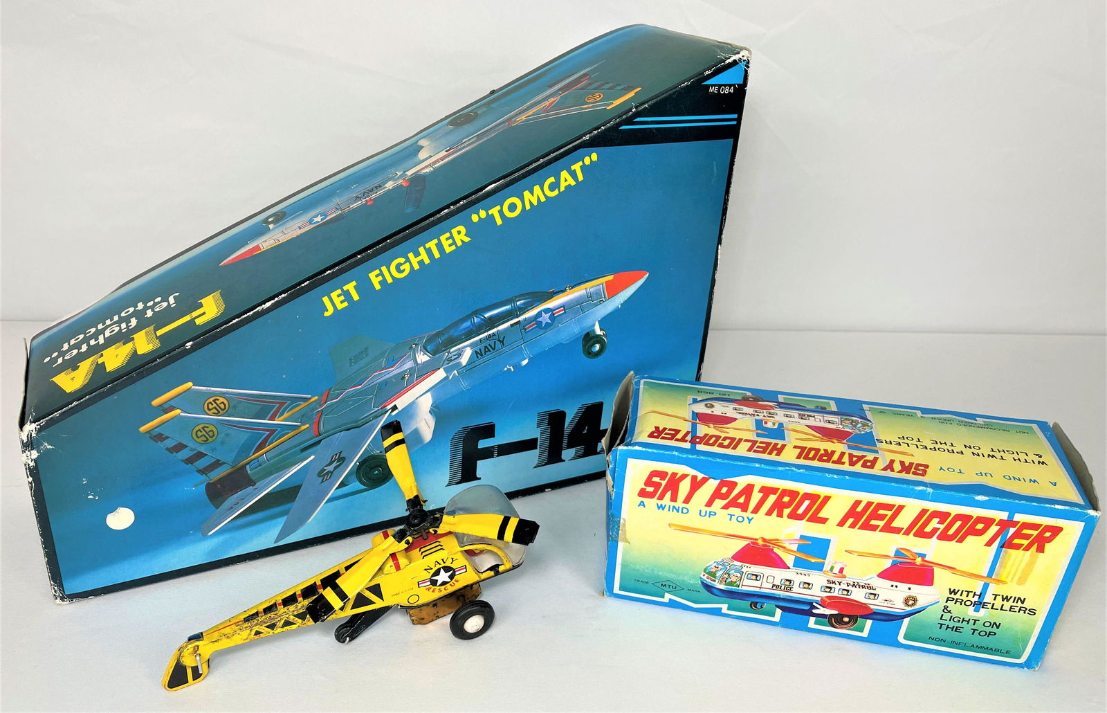 Three Tin Litho Toys Helicopters & Fighter Jet: Three (3) later vintage tin litho toys including a battery operated F-14A Tomcat Jet Fighter, a friction Sky Patrol helicopter, and a friction Navy Rescue helicopter. Tomcat and Sky Patrol are in boxe